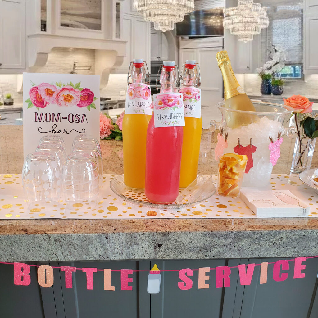 Mimosa bar and batch cocktails displayed with custom drink menu signage and themed glassware.