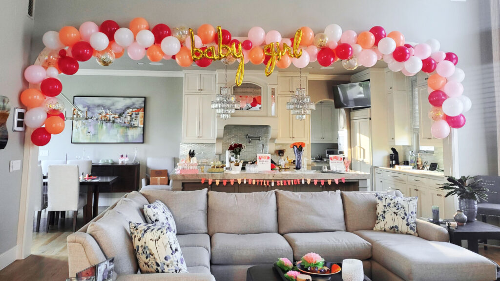 Wide view of the Champagne Brunch baby shower showing coordinated pink and gold décor, balloon garlands, buffet table, and seating area.