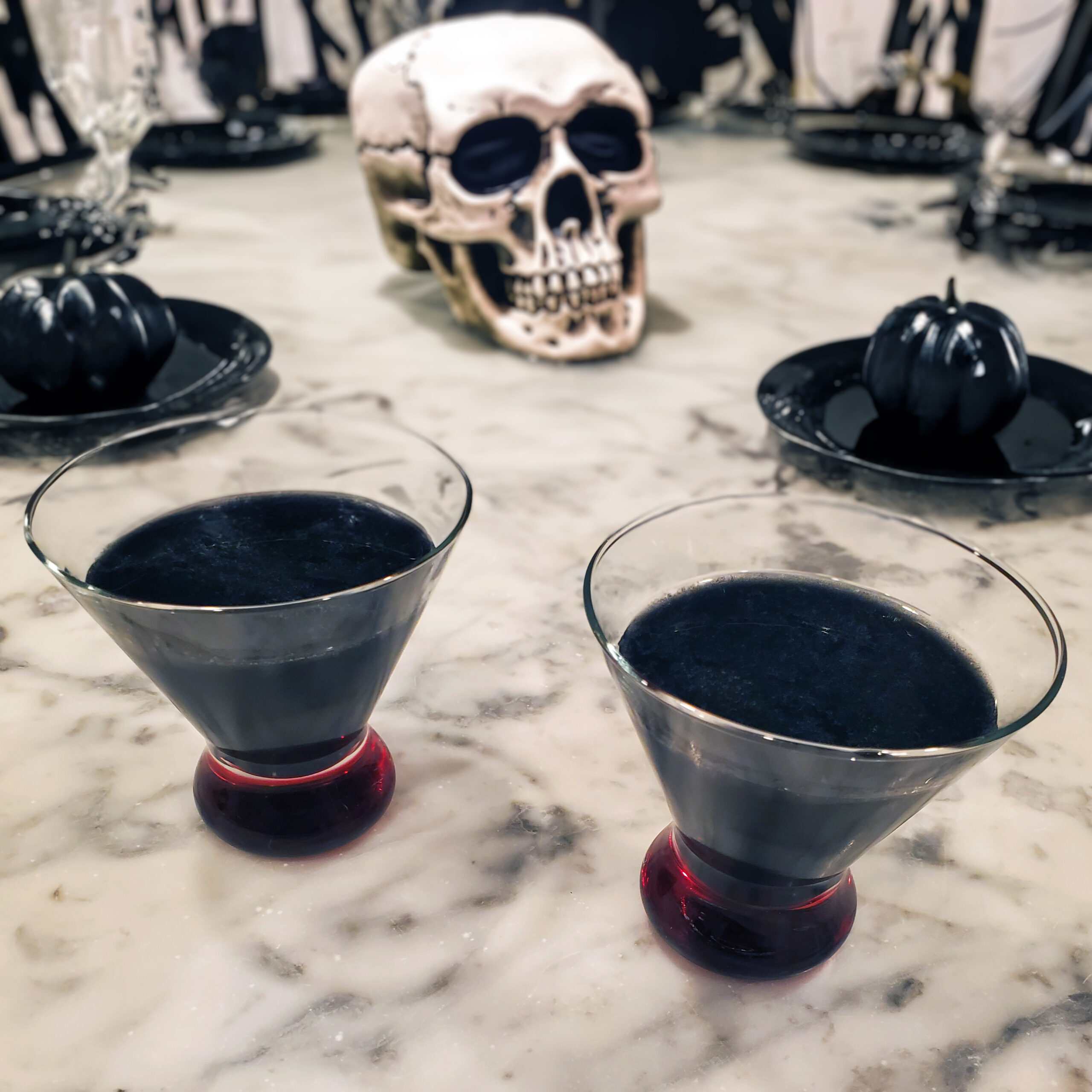 Jet-black Corpse Reviver cocktail served in a coupe glass with a citrus garnish.