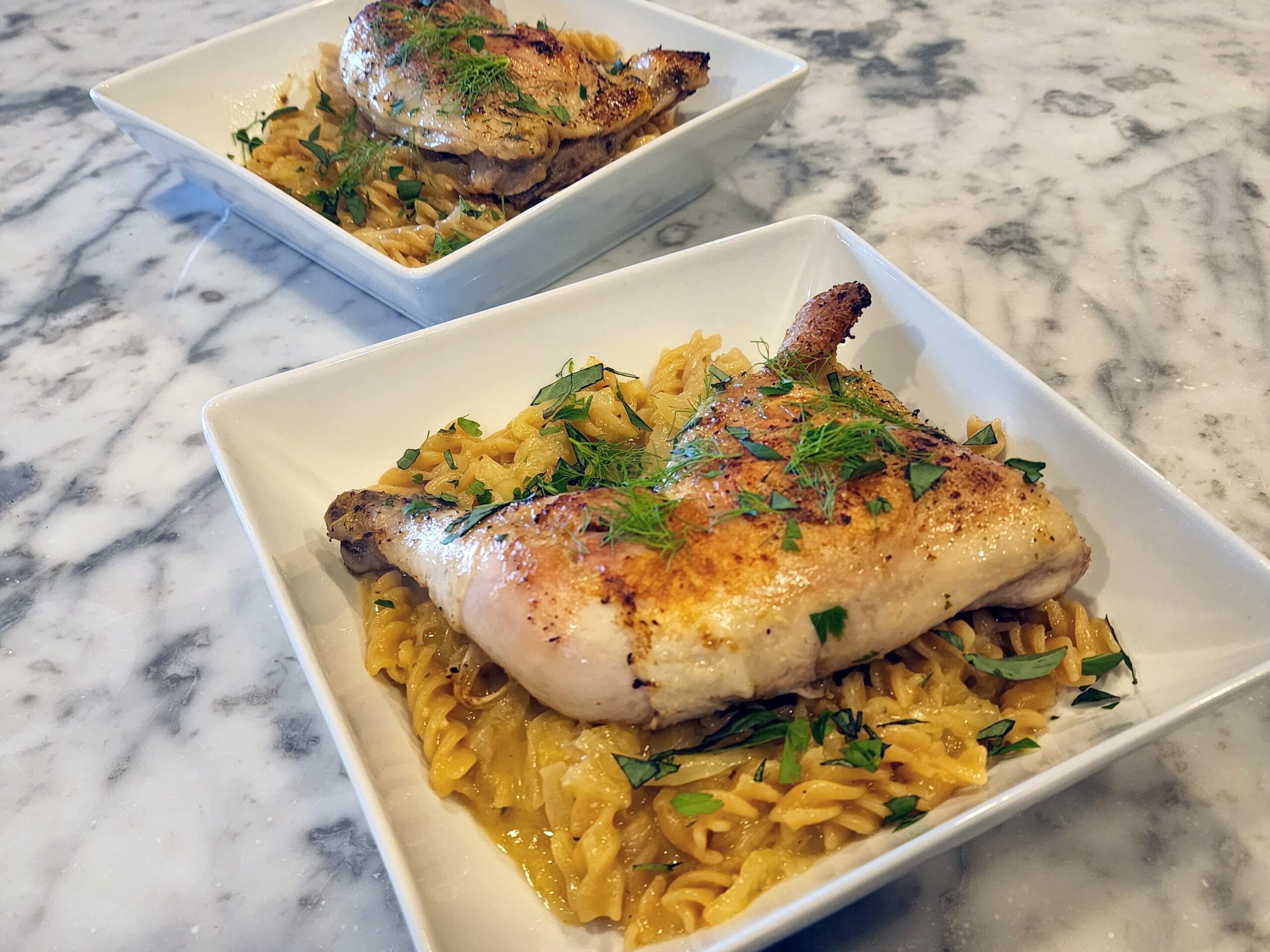 Finished chicken fennel pasta served straight from the pan, garnished with fresh parsley and fennel fronds