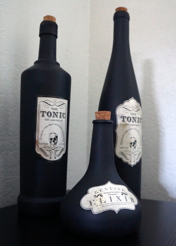 DIY potion bottles displayed on a fireplace mantle, mixed with different bottle shapes for a spooky, eclectic look.
