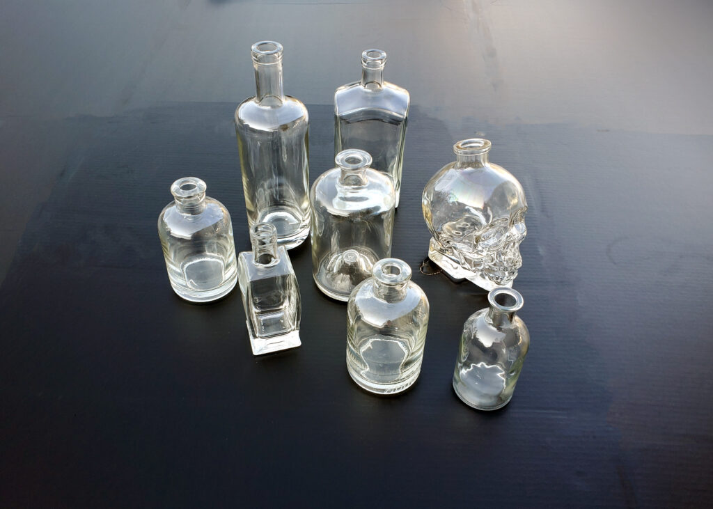 Assorted empty glass bottles in various shapes and sizes, cleaned and ready to be turned into DIY potion bottles.