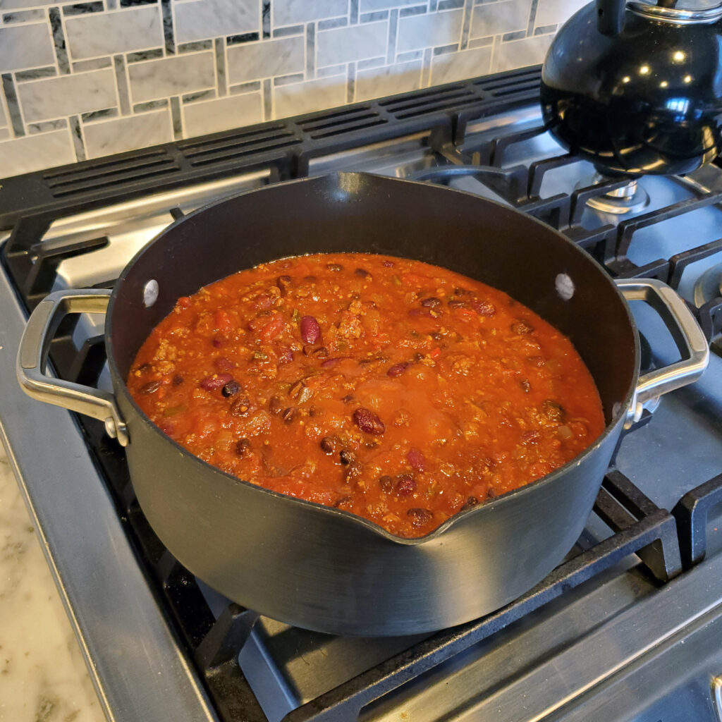 Close-up of chili as it cooks, showing rich texture and color from smoky spices.