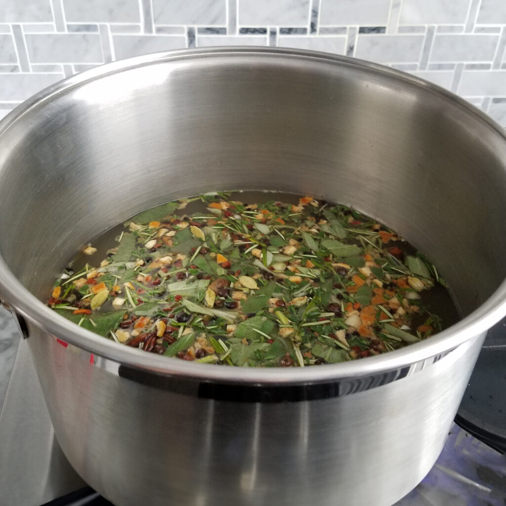Large stockpot filled with apple cider turkey brine containing citrus wedges, herbs, and spices simmering on the stove.