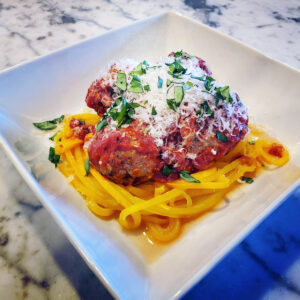 Beef and pork meatballs served over zucchini noodles with tomato sauce.