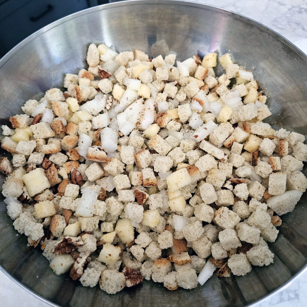 Cornbread stuffing mix with chopped pecans, apples, and onions ready for mixing.