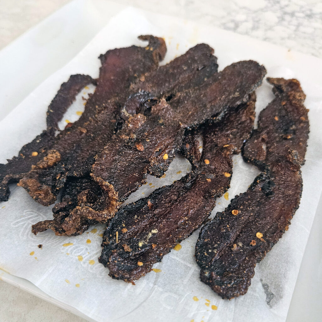Close-up of crisp edges and caramelized sugar bubbling on baked bacon.