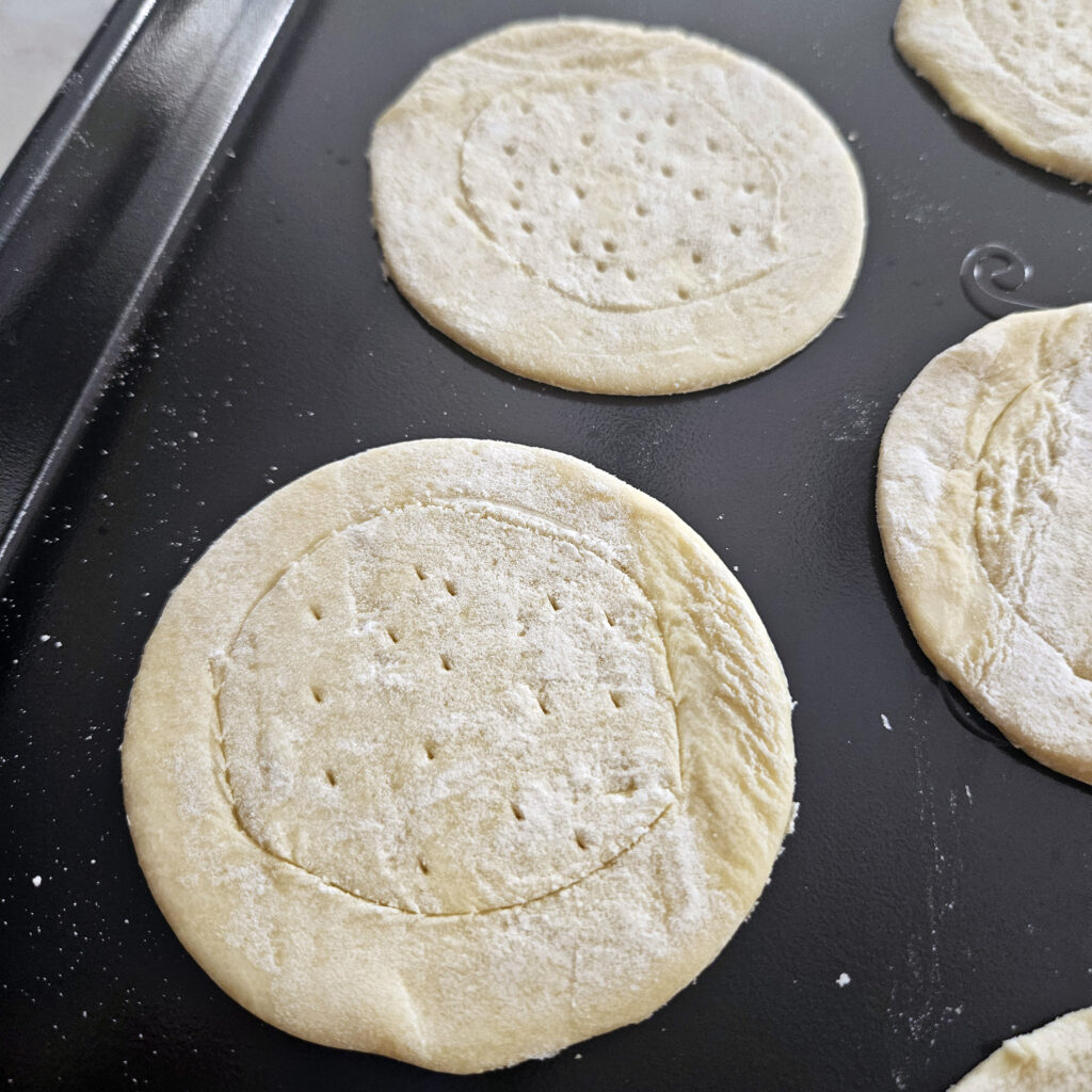 Rolled puff pastry cut into circles on a floured surface before baking.