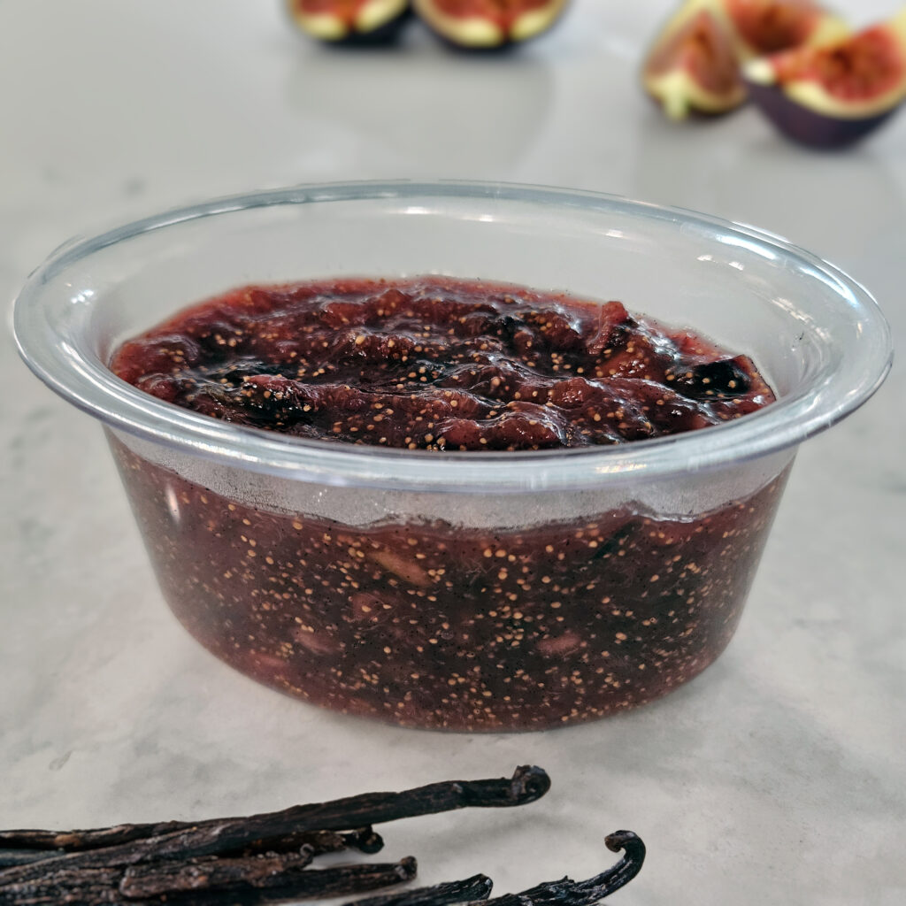 Homemade fig jam spooned into pint-sized jars and cooling.