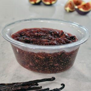 Homemade fig jam spooned into pint-sized jars and cooling.