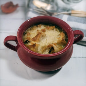 Finished soup topped with toasted baguette slices and melted cheese.