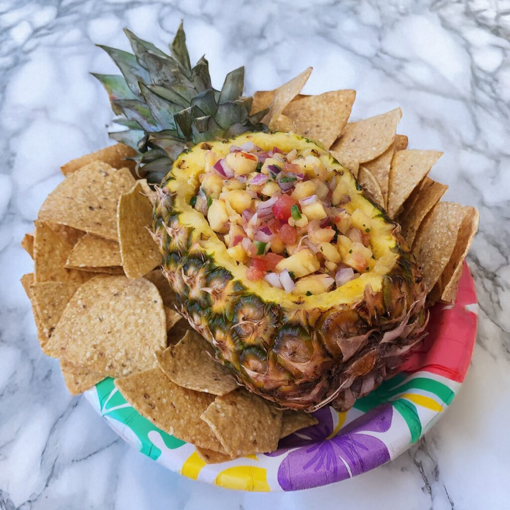Fresh pineapple salsa served inside a hollowed-out pineapple, garnished and ready for dipping.