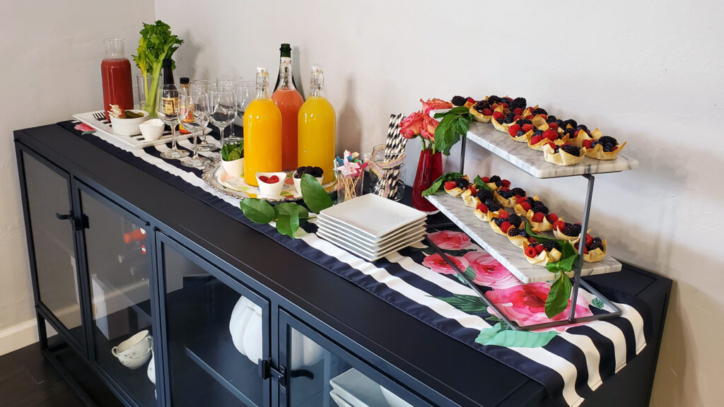 Long spring brunch buffet table with pastries, deviled eggs, and candy bacon.