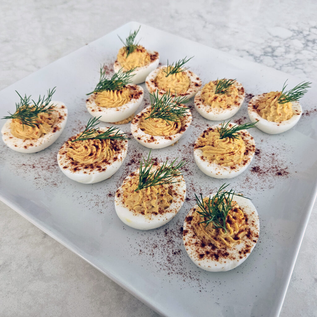 A full tray of Bloody Mary deviled eggs ready to serve at a brunch table.