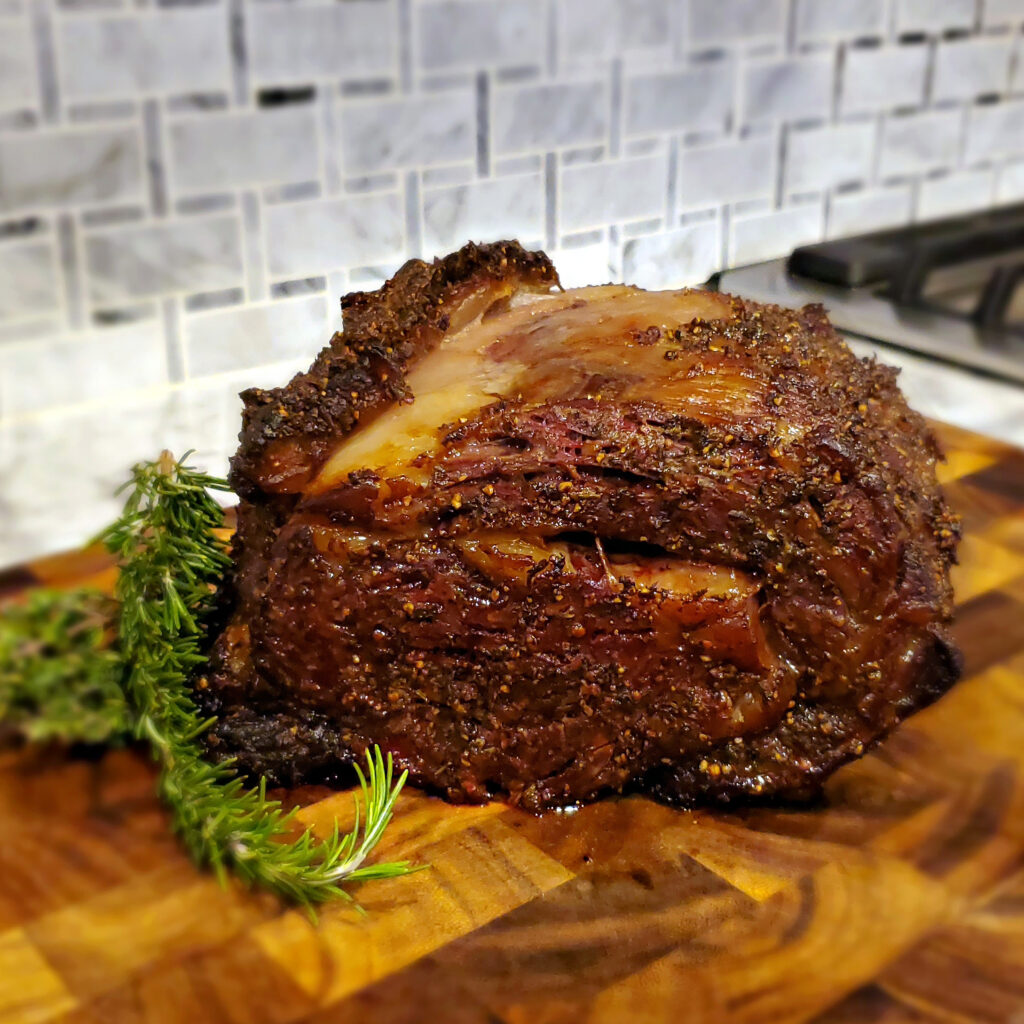 Finished prime rib with a golden crust resting before slicing.