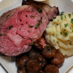 Prime rib served as the centerpiece of a Christmas dinner table with sides and sauces.