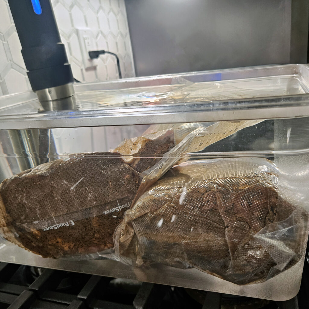 Prime rib sealed in a sous vide bag submerged in a temperature-controlled water bath.