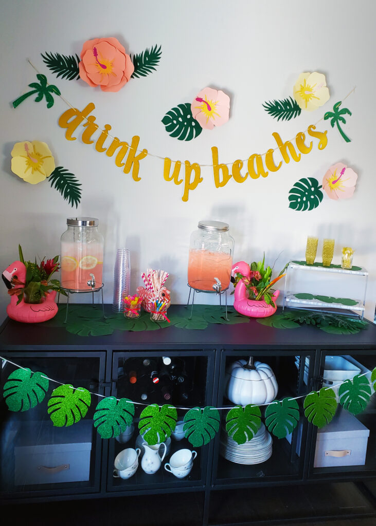 Luau party buffet table decorated with pineapples, palm leaves, and tropical serving trays.
