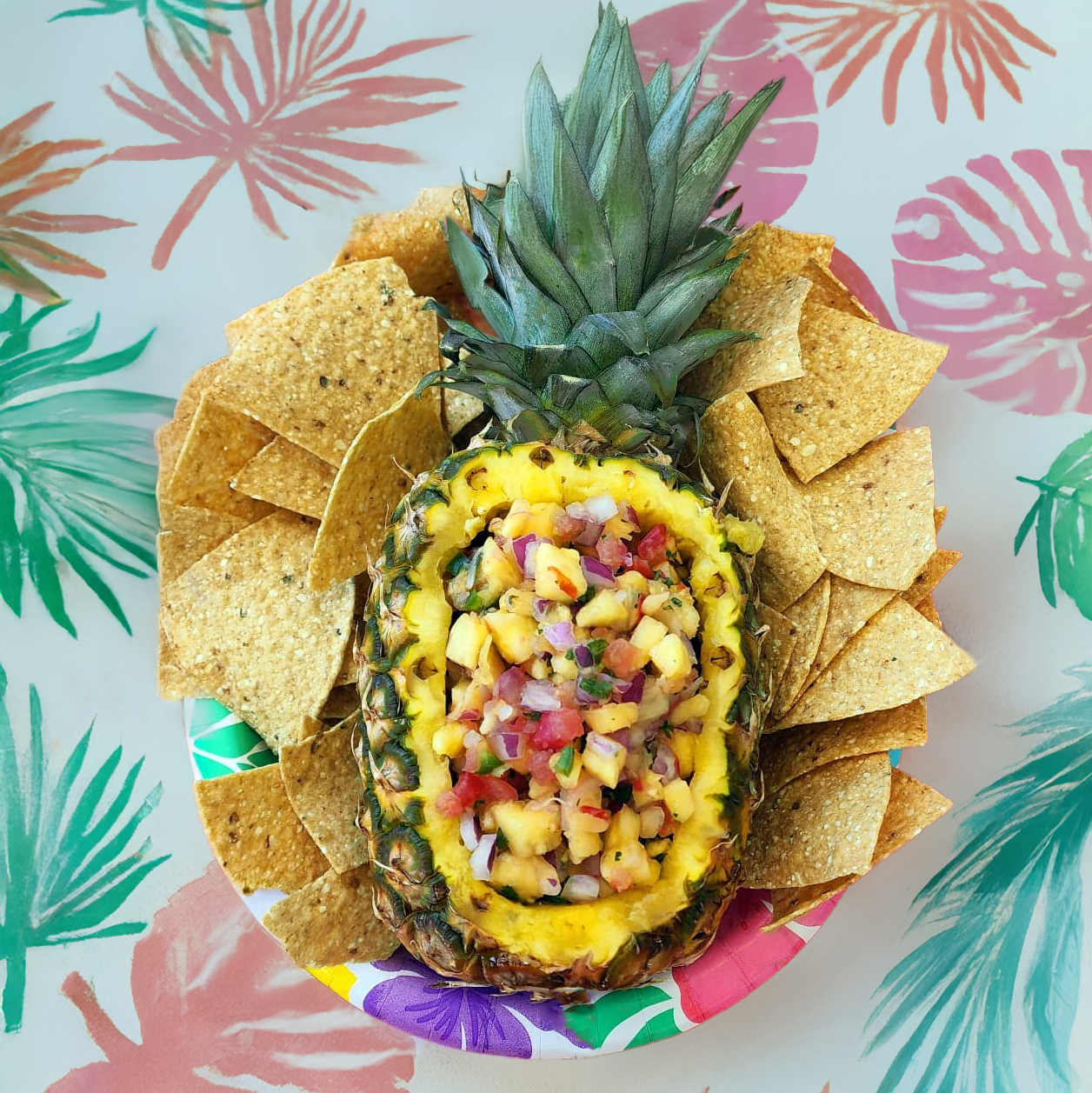 Pineapple salsa displayed on a summer party table with tortilla chips nearby.