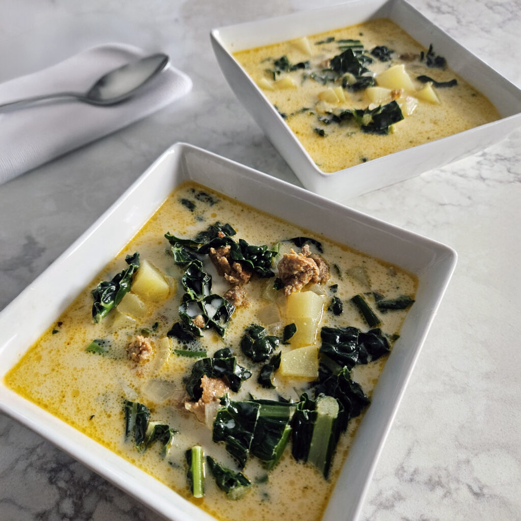 Hearty bowl of Italian sausage zuppa with creamy broth and tender potatoes.
