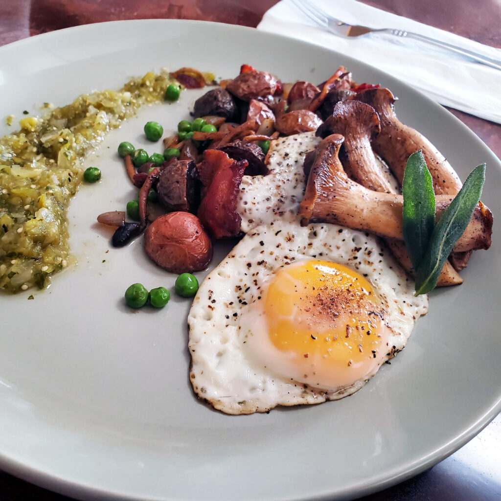 Heirloom potato hash with king oyster mushrooms, honey ham, peas, fried sage, and a sunny-side-up egg finished with salsa verde.