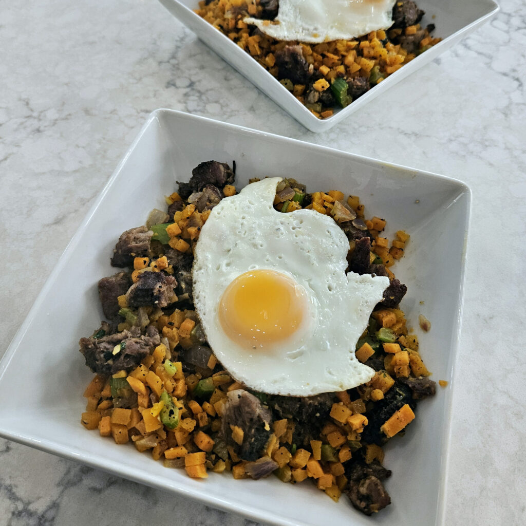 Breakfast hash made with leftover prime rib, sweet potato, butternut squash, red onion, celery, and a sunny-side-up egg.