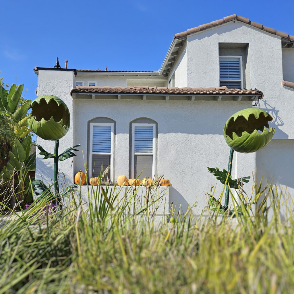 Two giant Venus fly trap decorations standing tall in a front yard, flanking a walkway like oversized carnivorous plants.