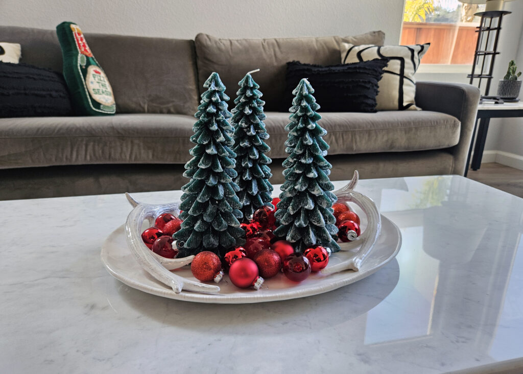 Holiday coffee table styled with ceramic pine trees, red ornaments, and winter greenery.Holiday coffee table styled with ceramic pine trees, red ornaments, and winter greenery.