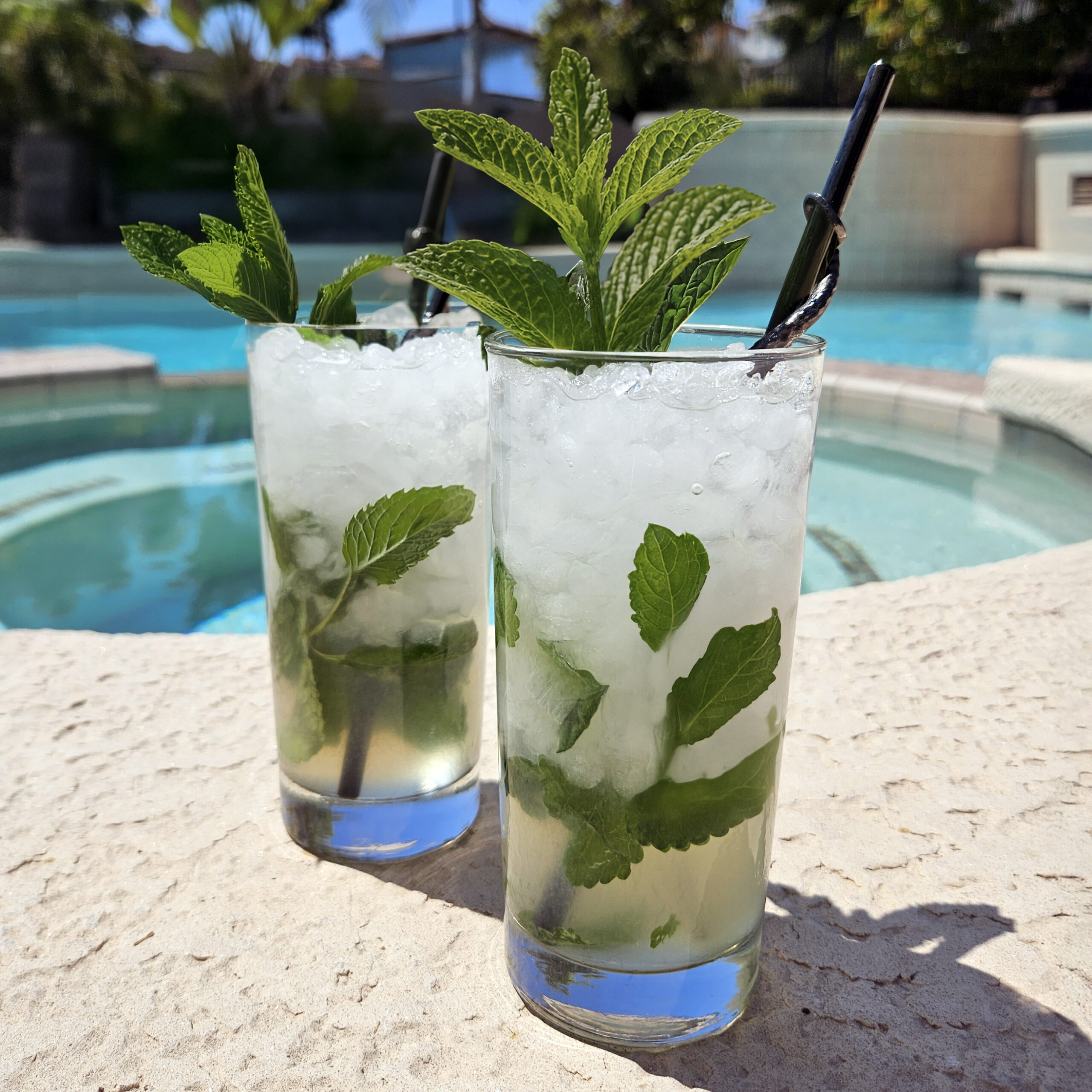 Classic mojito cocktail in a clear glass filled with ice, fresh mint leaves, and lime wedges, topped with club soda and condensation on the glass.
