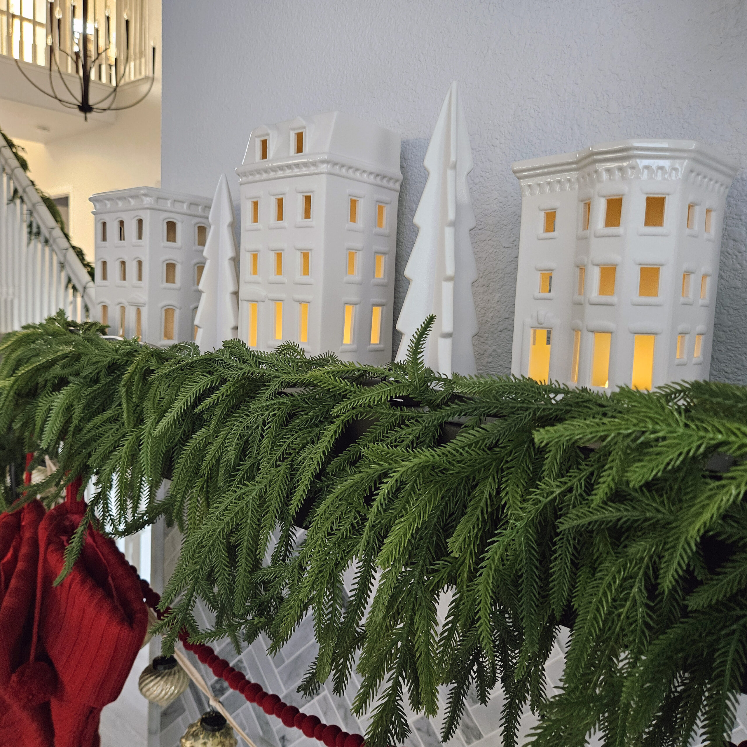 Christmas village pottery houses on black mantle with fir tree garland