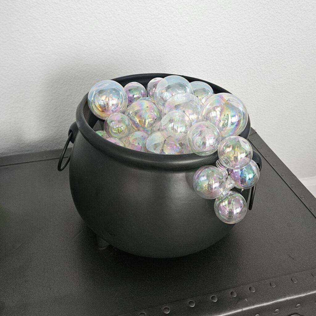 Clear plastic ornaments threaded with fishing line to create clustered bubble shapes for a DIY cauldron display.